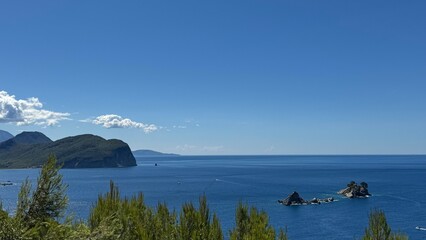 Budva, Montenegro - July 20, 2025: Serene coastal landscape with blue ocean and distant mountains in view