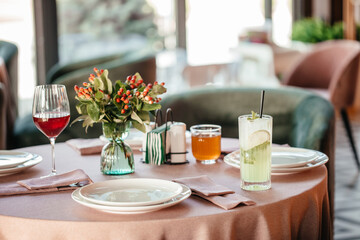 Elegant restaurant table setting with drinks, floral centerpiece, and natural daylight ambiance.