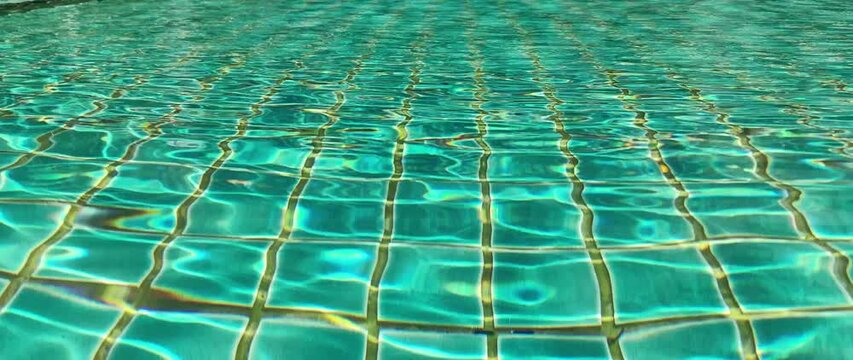 Pool with clear water is lined with blue-green tiles. Calm water is reflected in tile and creates serene atmosphere
