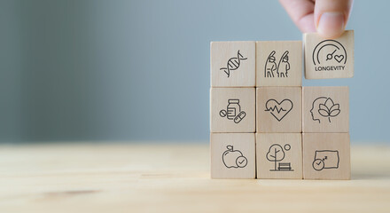 Health and longevity, longevity economy concept. Wooden blocks with icons related to health, genetics, aging and longevity. A holistic approach to a healthy lifestyle and extended life expectancy.