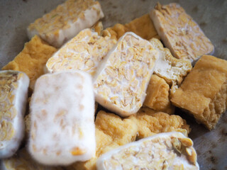 Raw pieces of tempeh on a frying pan.