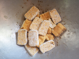 Raw pieces of tempeh on a frying pan.