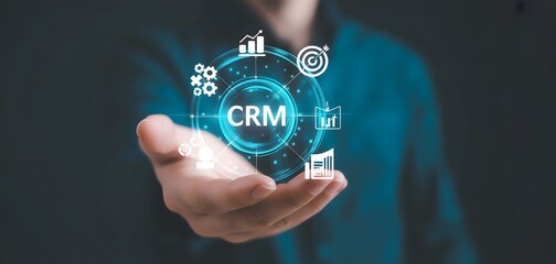 Obraz premium Digital CRM and Futuristic Hands: A close-up of a hand cradling a digital interface showcasing 'CRM,' surrounded by sleek icons representing business analytics.