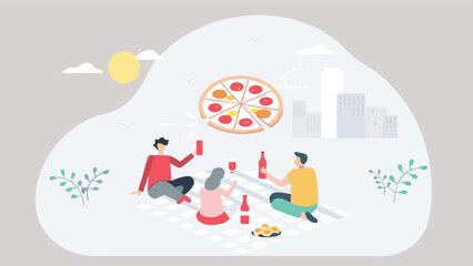 People enjoying a picnic with pizza and drinks in a park with city buildings in the background scene