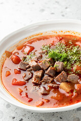 Homemade beef stew with tender meat, diced vegetables, and fresh parsley garnish served in a white bowl on a speckled countertop, shot from above.