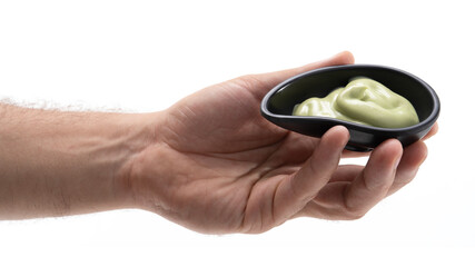 Hand holding a small bowl of green sauce