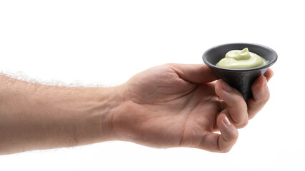 Hand holding a small bowl of green sauce