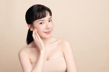 A beautiful young Asian woman with clean, fresh skin against a beige background. Skincare, facial...