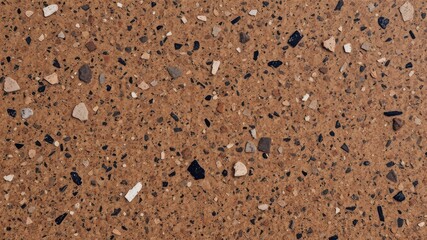 Close up of a brown surface with embedded small stones and pebbles of various colors and shapes