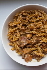 Delicious creamy pasta with chanterelle mushrooms served in a white bowl. Top down food shot for recipe blogs, cooking magazines, or restaurant menus. Rustic comfort food at its best.