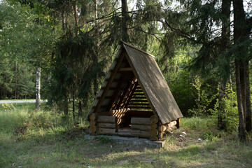 a gazebo in the form of a hut for recreation in the forest on the roadside, and garbage nearby. social problems
