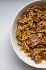 Delicious creamy pasta with chanterelle mushrooms served in a white bowl. Top down food shot for recipe blogs, cooking magazines, or restaurant menus. Rustic comfort food at its best.