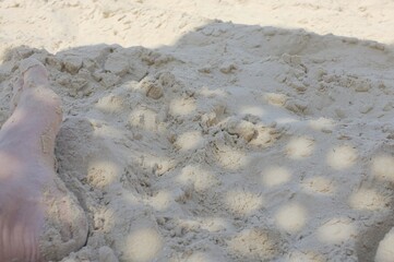 Foot in the Sand The photo shows a foot partially covered by light, loose sand.