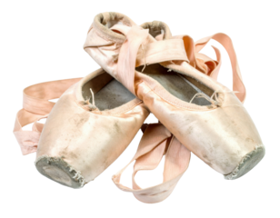 Worn pink ballet slippers with ribbons, showcasing their delicate fabric and scuffed soles, symbolizing the artistry of dance.
