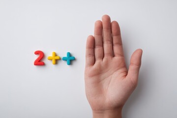 Hand next to 2 in primary colors on white