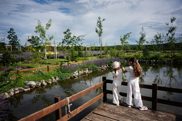 Fototapeta premium Two young girls enjoying a tranquil park by a beautiful pond