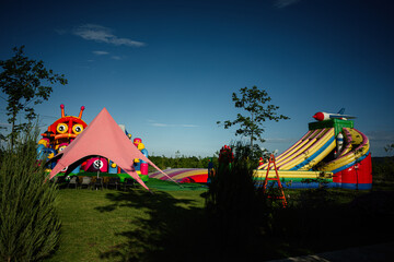 Colorful inflatable playground with slides and tents in a lush outdoor park
