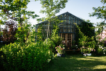 Cozy wooden greenhouse surrounded by lush green plants and colorful flowers