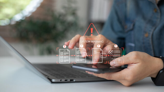 Close-up hand using smartphone with system warning alert interface, showing document scanning, data protection risk, and cybersecurity notification on digital screen.