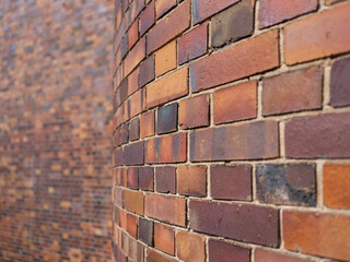 curved brick wall in focus, with a second flat brick wall softly blurred in the background