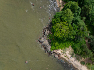 Top down photo of a transitional zone where sandy beach meets rocky terrain. In the center, a...