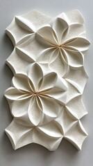 A white, wall - mounted, folded - paper - like sculpture with floral shapes