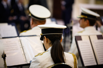 Unrecognizable woman seen from behind playing in a military orchestra