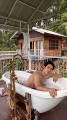 Handsome Man Relaxing in Bubble Bath on Veranda Amidst Lush Green Forest and Gentle Rain