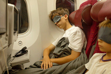 Teenage child, boy, sleeping on board of aircraft, traveling on vacation with parent and siblings going for a summer holiday