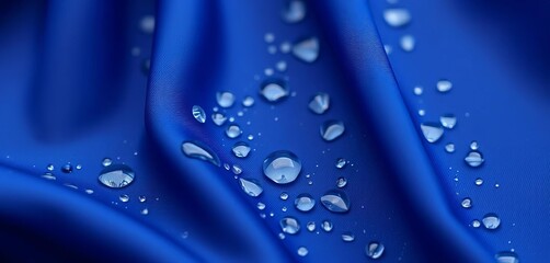 Clear water droplets beading on smooth, dark blue fabric, photography, abstract