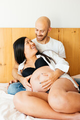 Smiling Couple Enjoying Tender Moments Together in Bed as They Await Their New Arrival