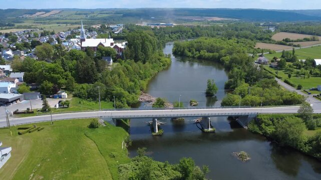 Aerial view of the municipality of Price until passing under the On&eacute;sime-Gagnon bridge crossing the La Mitis salmon fishing river crossed by a few cars. City of Price, Quebec, Canada, 2025.