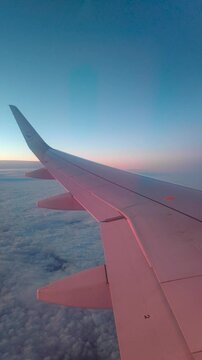 Airplane flying above clouds, during sunrise morning sky.