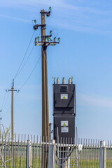 village transformer substation and power transmission pole against blue sky