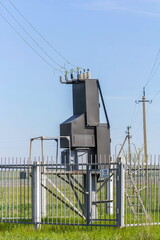 village transformer substation and power transmission pole against blue sky