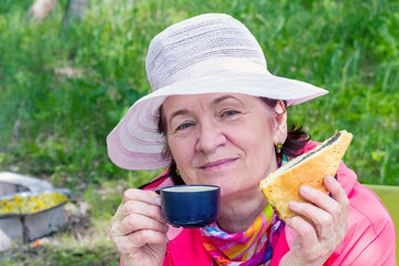 beautiful mature women drinking tea with pie outdoors on a sunny day