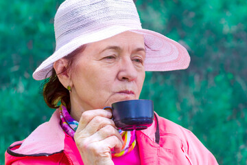 beautiful mature women drinking tea with pie outdoors on a sunny day
