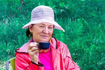 beautiful mature women drinking tea with pie outdoors on a sunny day