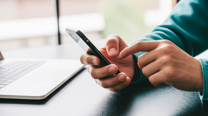 A businesswoman uses her mobile phone while working on a laptop at the office table, surfing the internet and searching for information on her smartphone.
Man using tablet computer and phone