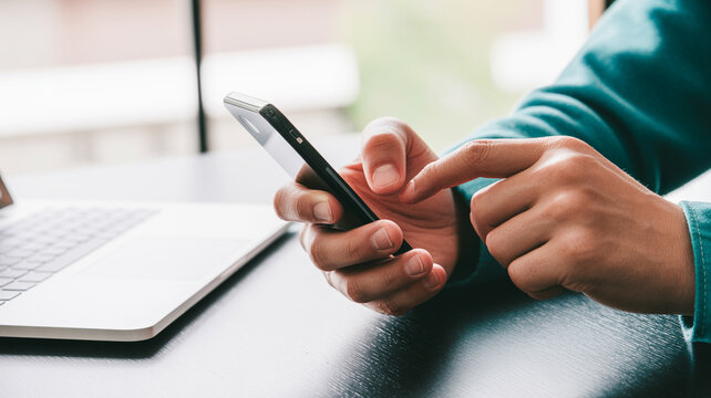 A businesswoman uses her mobile phone while working on a laptop at the office table, surfing the internet and searching for information on her smartphone.
Man using tablet computer and phone