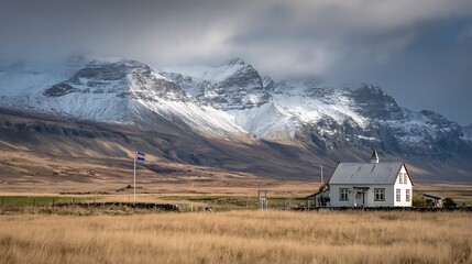 Isolated white house stands against majestic snow capped mountains under dramatic sky