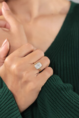 Close-up of a woman's hands wearing a gold ring with a large rectangular clear gemstone, showcasing...
