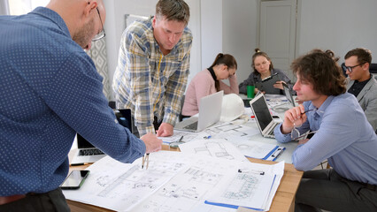 A group of specialists discusses construction issues. Engineers, designers and architects are working together on a smart home project