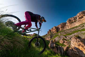 Mountain biker riding down a grassy slope. Enduro mountain bike. MTB against a mountain landscape