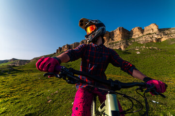 Sports. A cyclist stands alone in a field. A person riding a bicycle in a downhill style.
