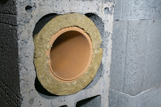 Close-up of chimney flue pipe with mineral wool insulation inside concrete block. Construction, heating system, fire safety, thermal insulation, ventilation, masonry.