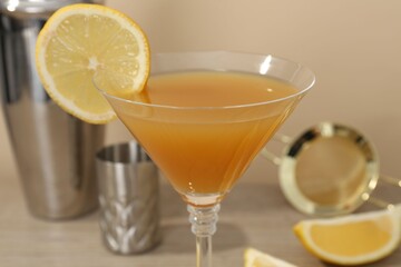 Tasty lemon cocktail in glass and bartender equipment on table, closeup