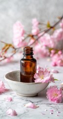 Amber bottle of oil, nestled in a shallow dish, surrounded by delicate pink cherry blossoms