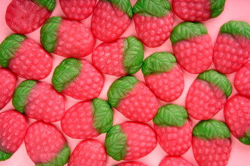 Pink background covered with delicious strawberry shaped candy