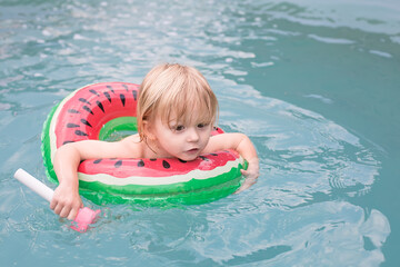 Child in Watermelon-Themed Inflatable Floating in a Pool